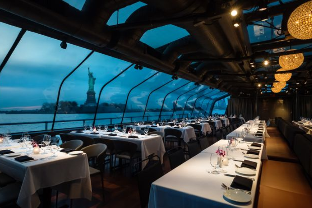 Bateaux New York Premier Plus Dinner Cruise - Vivi una notte magica a bordo del Bateaux New York Premier Plus Dinner Cruise. Salite su una bellissima barca con pareti di vetro e godetevi viste sorprendenti dello skyline di New York City. Rilassatevi con musica dal vivo mentre navigate lungo il fiume Hudson. Gustate una deliziosa cena di tre portate preparata dai migliori chef. Ammirate i famosi siti come la Statua della Libertà e il Brooklyn Bridge illuminati di notte. La barca offre un ambiente tranquillo e romantico, perfetto per momenti speciali. Che si tratti di una celebrazione o semplicemente di una bella serata, questa crociera la renderà indimenticabile. Vestitevi eleganti e preparatevi per una splendida serata sull'acqua Bateaux New York Premier Plus Dinner Cruise - Immagine 2 di 5