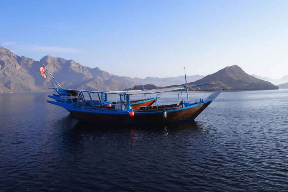 Khasab Tour - Full Day Dhow Cruise With Lunch - Full Day Dhow Cruise to Khor Sham with our traditionally decorated Omani wooden dhows in azure water through a majestic fjord (Khor), surrounded by spectacular mountains and serene remote white sand beaches. At the entrance of the fjord, our guests can enjoy dolphin watching. Khasab Tour - Full Day Dhow Cruise With Lunch - Image 1 of 5