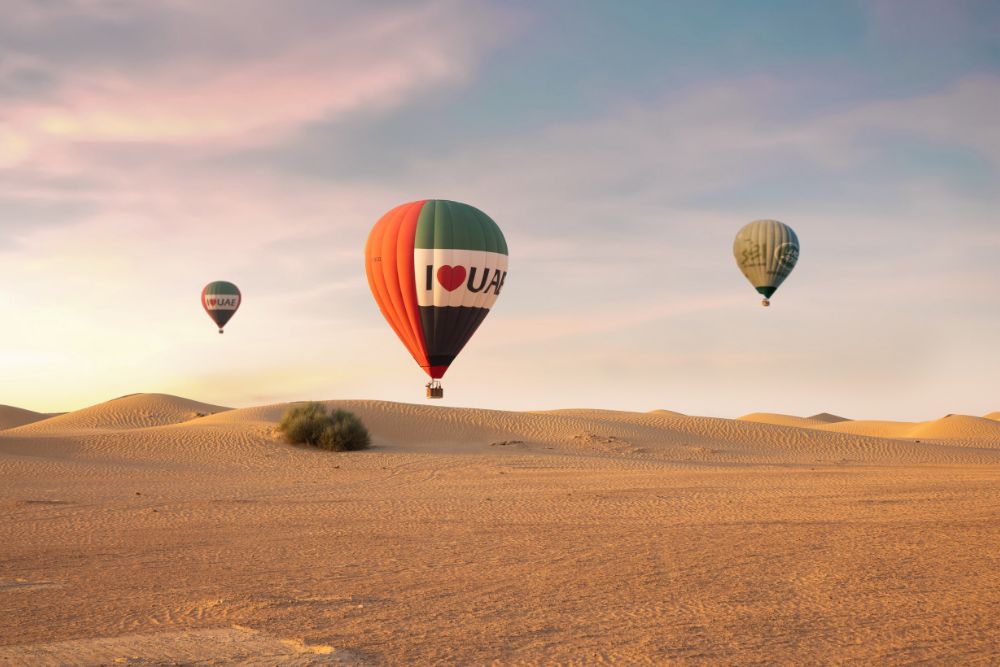 Dubai Hot Air Balloon Signature Experience - "Experience a breathtaking sunrise hot air balloon ride over Dubai’s desert with a drone light show, in-flight falcon display, and exclusive views of the Dubai Desert Conservation Reserve. Complete the journey with a Michelin-starred breakfast and a camel ride at a Royal Desert Retreat." Dubai Hot Air Balloon Signature Experience - Image 1 of 5