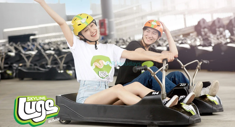 스카이라인 루지 부산 - 스카이라인 루지 부산에서 짜릿한 트랙을 미끄러지며 경치 좋은 풍경을 즐겨보세요. 스카이라인 루지 부산에서는 각각 100미터 이상의 내리막 즐거움이 있는 네 가지 독특한 루지 트랙 중 선택할 수 있습니다. 스카이라인 루지 부산의 스카이라이드로 오시리아 테마파크와 동부 산맥의 멋진 전경을 감상해보세요. 모험을 원하든 아름다운 경치를 원하든, 스카이라인 루지 부산은 모두를 위한 무언가를 제공합니다. 스카이라인 루지 부산에서 잊지 못할 경험을 놓치지 마세요! 스카이라인 루지 부산 - 이미지 1 중 5
