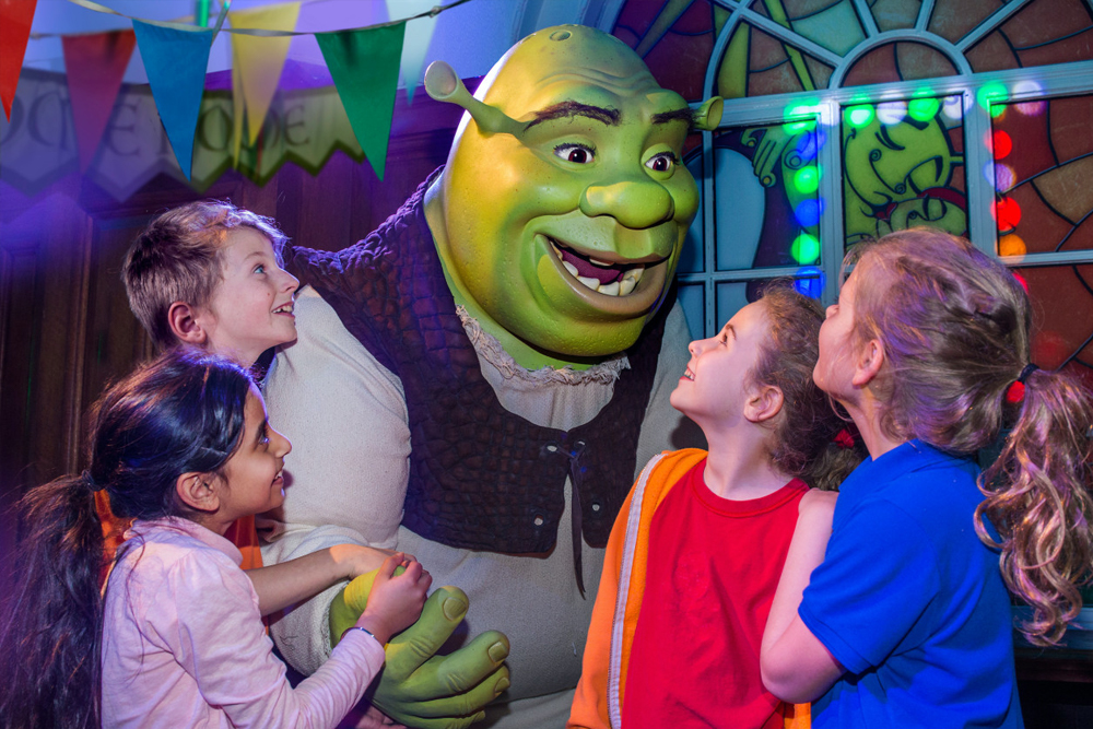 L'Aventure de Shrek à Londres - Entrez dans l'univers de Shrek avec L'Aventure de Shrek à Londres, une expérience interactive pleine de divertissement pour tous les âges. Profitez d'un trajet en bus volant 4D, de spectacles en direct et d'effets spéciaux lors de votre voyage à Très Très Loin. Rencontrez Shrek, l'Âne et d'autres personnages adorés. Réservez vos billets pour L'Aventure de Shrek à Londres dès aujourd'hui ! L'Aventure de Shrek à Londres - Image 5 sur 5