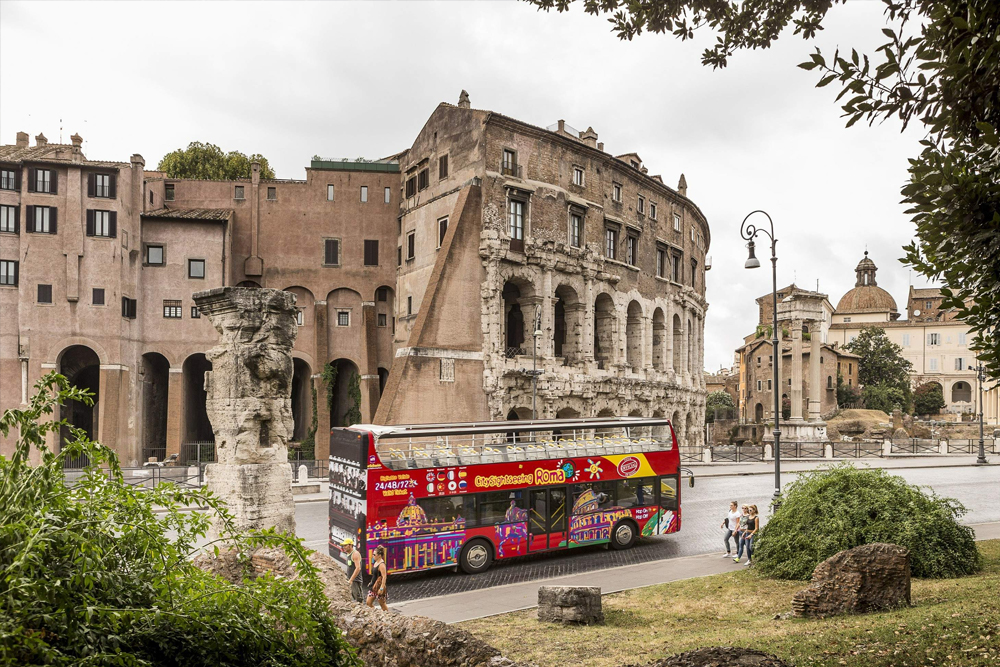 Римский автобус hop-on hop-off от City Sightseeing - Исследуйте Рим с автобусом hop-on hop-off City Sightseeing и посещайте главные достопримечательности в своем темпе. Путешествуйте на двухэтажном автобусе с открытым верхом с потрясающими видами на Колизей, Ватикан и многое другое. Наслаждайтесь аудиогидом на нескольких языках, открывая для себя историю и культуру Рима. Выбирайте билеты на 24, 48 или 72 часа для гибкого экскурсионного опыта. Римский автобус hop-on hop-off от City Sightseeing - Изображение 1 из 5